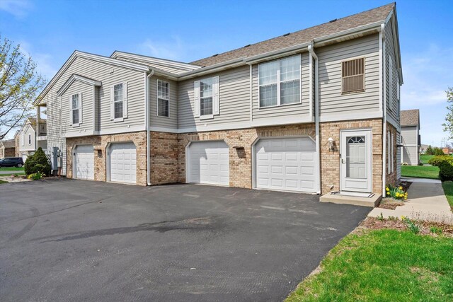 multi unit property featuring brick siding, a garage, and driveway