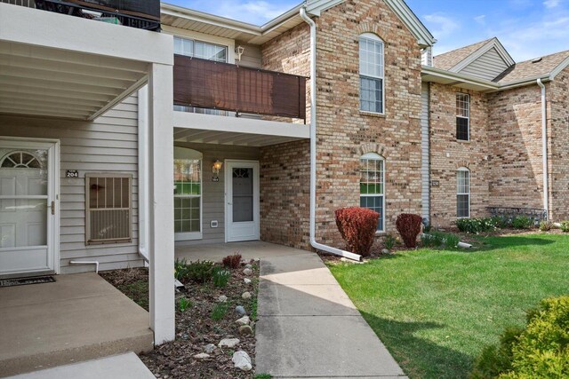 exterior space featuring brick siding, a yard, and a balcony