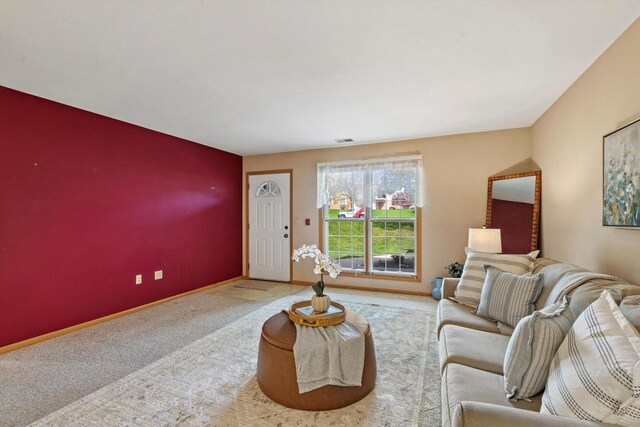 carpeted living area with baseboards and an accent wall