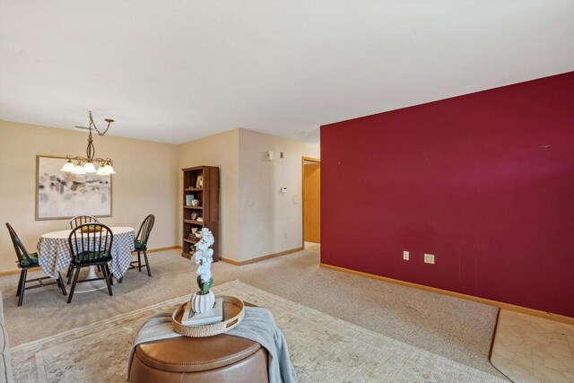 carpeted living area featuring baseboards and an inviting chandelier