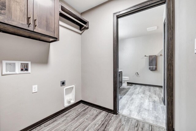 washroom with cabinet space, electric dryer hookup, light wood finished floors, and hookup for a washing machine