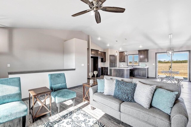living area featuring ceiling fan, plenty of natural light, lofted ceiling, and light wood-type flooring