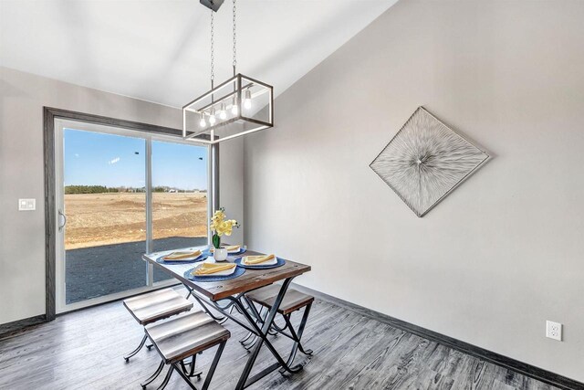 dining area featuring an inviting chandelier, baseboards, and wood finished floors