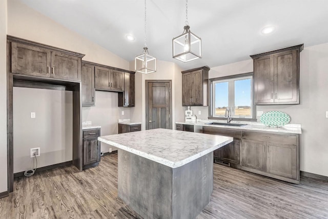 kitchen with a sink, light wood-style floors, a kitchen island, and dark brown cabinets