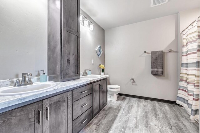 bathroom with double vanity, visible vents, a sink, and wood finished floors