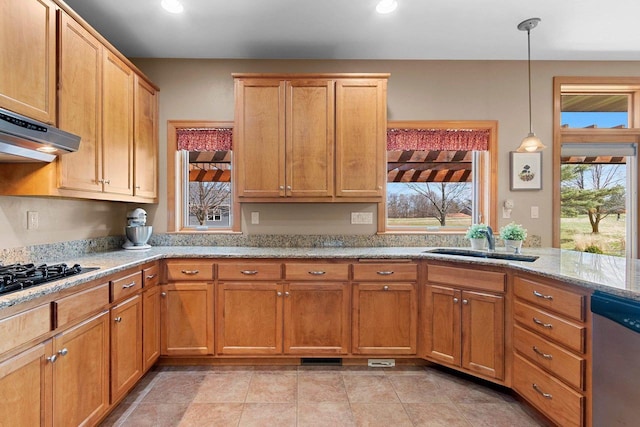 kitchen with stainless steel dishwasher, light stone countertops, a sink, black gas stovetop, and under cabinet range hood