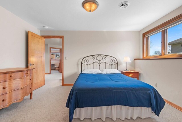 bedroom with baseboards, visible vents, and light colored carpet
