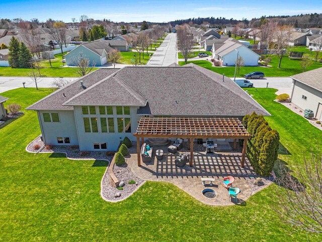 rear view of house with a lawn, roof with shingles, a residential view, and a patio area