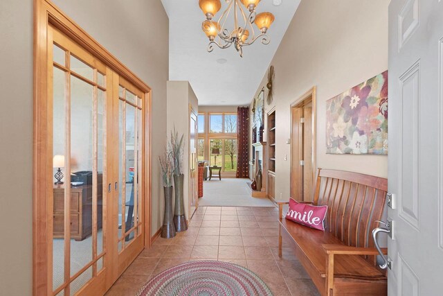 hallway featuring baseboards, tile patterned floors, a notable chandelier, and french doors