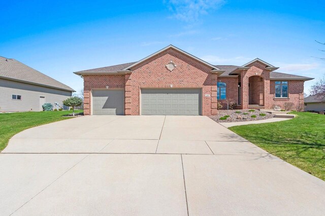 view of front of property featuring brick siding, an attached garage, driveway, and a front lawn