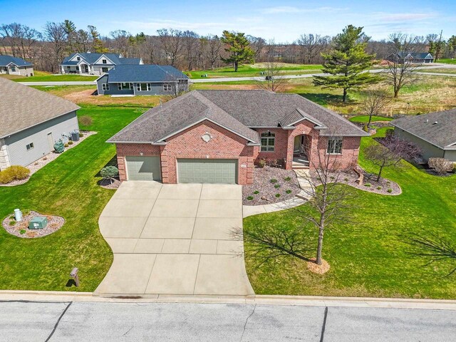 single story home featuring an attached garage, concrete driveway, a front yard, and brick siding