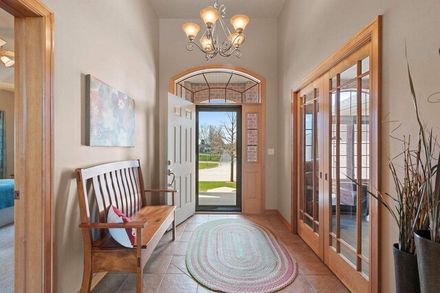 foyer entrance featuring an inviting chandelier, tile patterned flooring, and french doors