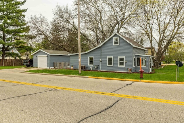 304 Mitchell St, Belleville, WI 53508 - view of front of house featuring fence, a front lawn, a garage, an outdoor structure, and driveway