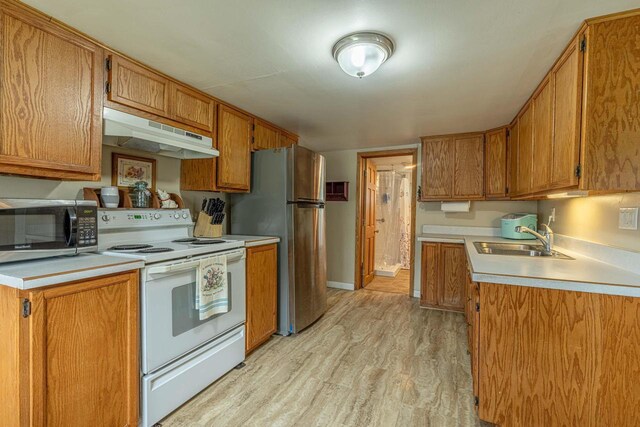 304 Mitchell St, Belleville, WI 53508 - kitchen featuring appliances with stainless steel finishes, a sink, brown cabinetry, light wood-style flooring, and under cabinet range hood