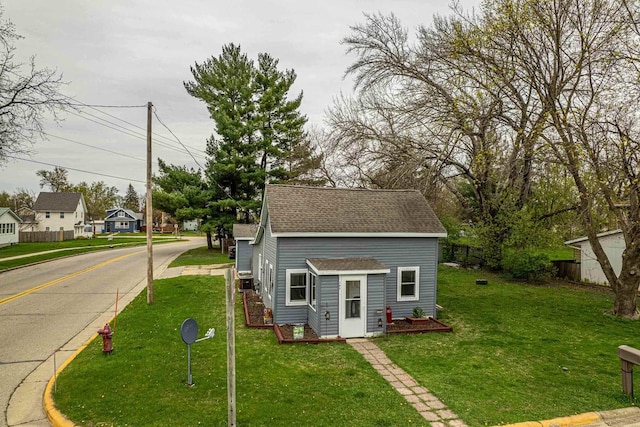 304 Mitchell St, Belleville, WI 53508 - exterior space featuring a shingled roof, a front lawn, fence, and an outbuilding