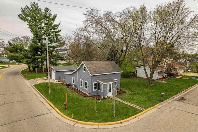 304 Mitchell St, Belleville, WI 53508 - view of front of house featuring an outdoor structure, a shingled roof, cooling unit, and a front lawn