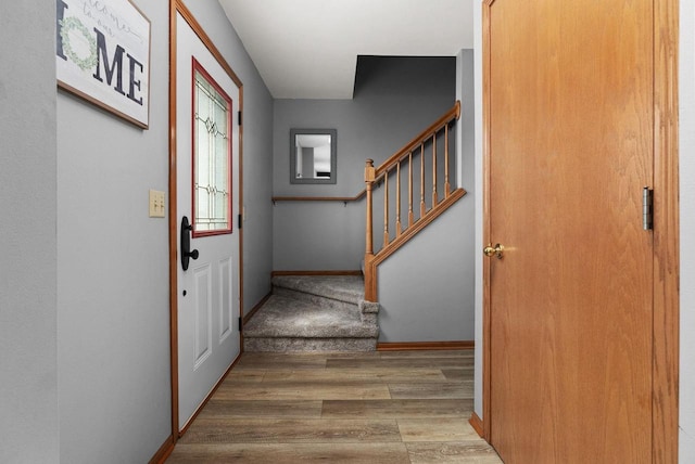 foyer entrance featuring baseboards, wood finished floors, and stairway