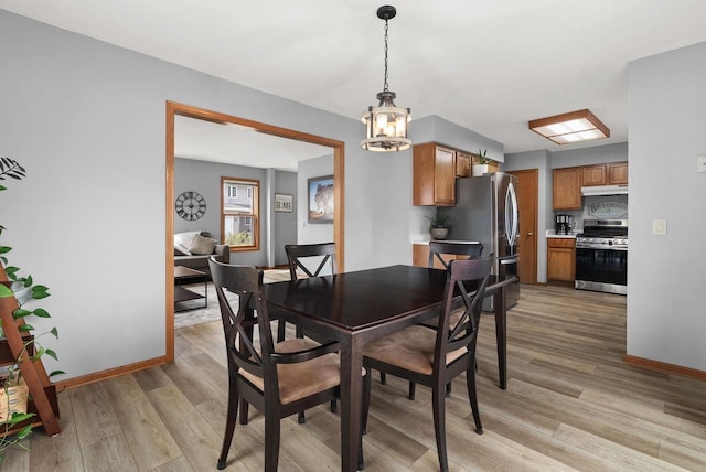 dining space featuring baseboards, an inviting chandelier, and light wood-type flooring