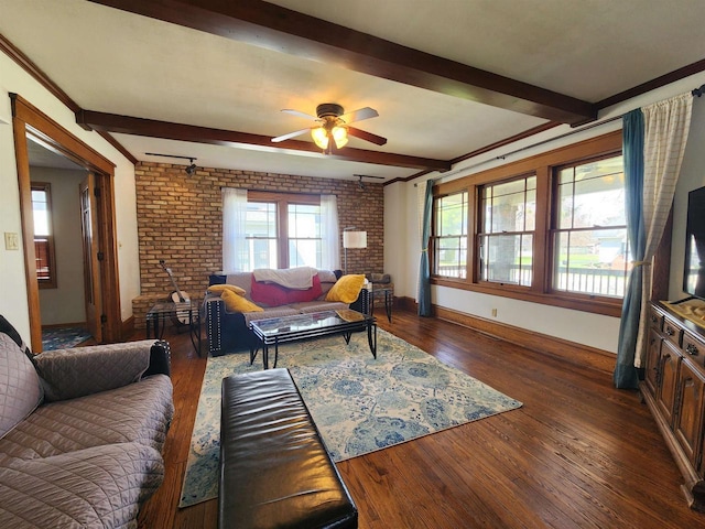 living area featuring ceiling fan, brick wall, beam ceiling, baseboards, and dark wood-type flooring