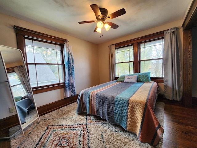 bedroom with ceiling fan, baseboards, multiple windows, and wood finished floors