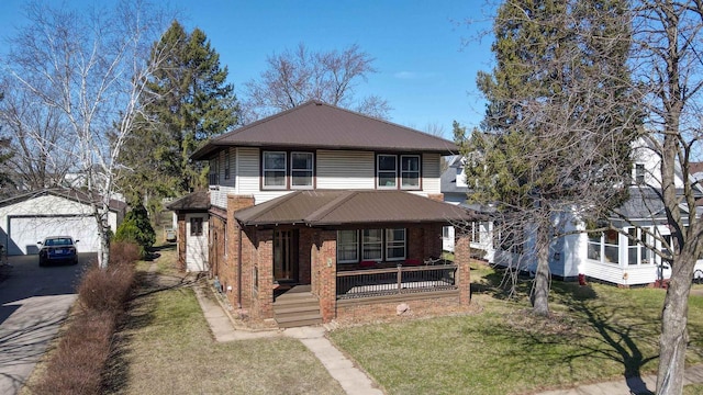 view of front facade featuring an outdoor structure, a front lawn, brick siding, metal roof, and a porch