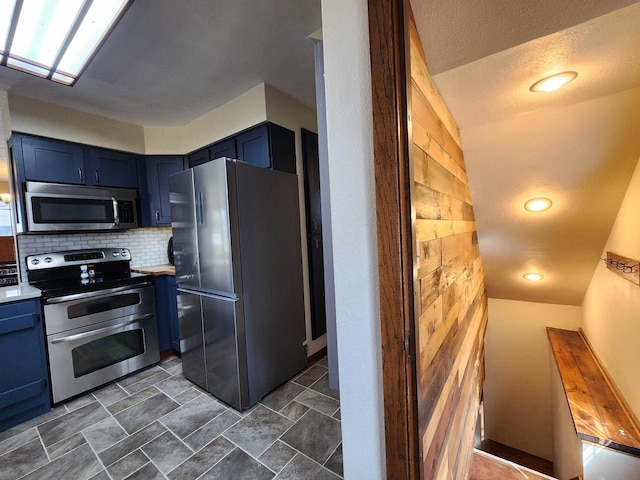 kitchen featuring decorative backsplash, appliances with stainless steel finishes, and blue cabinetry