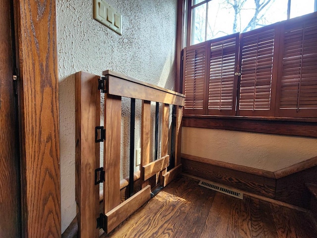 stairway featuring visible vents, a textured wall, and wood finished floors