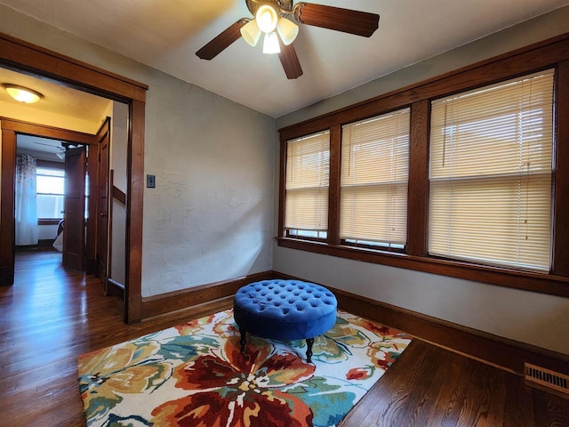 interior space with baseboards, ceiling fan, wood finished floors, and visible vents