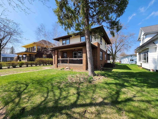 exterior space featuring brick siding, ceiling fan, a front yard, and a porch