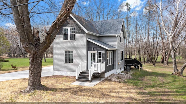 view of front of property with concrete driveway, roof with shingles, and a front lawn