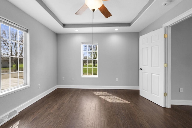 spare room with plenty of natural light, dark wood finished floors, ceiling fan, and visible vents