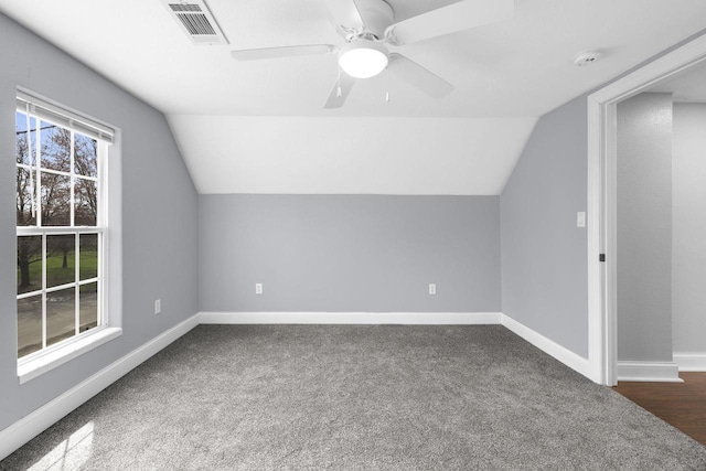 bonus room with baseboards, vaulted ceiling, dark colored carpet, and visible vents