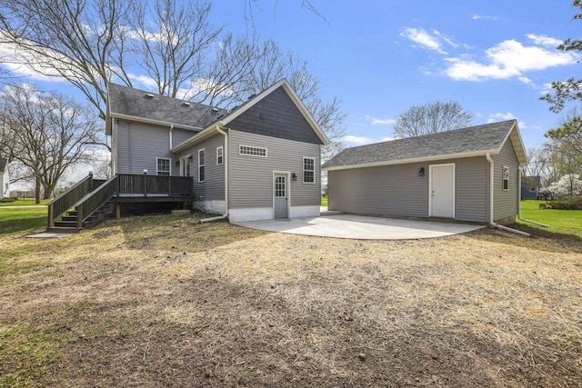 back of property with a yard, a patio, a shingled roof, and a deck