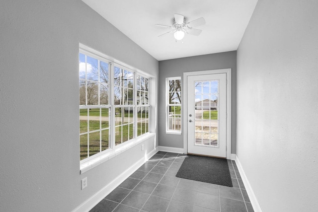 entryway with baseboards, a textured wall, ceiling fan, and dark tile patterned flooring