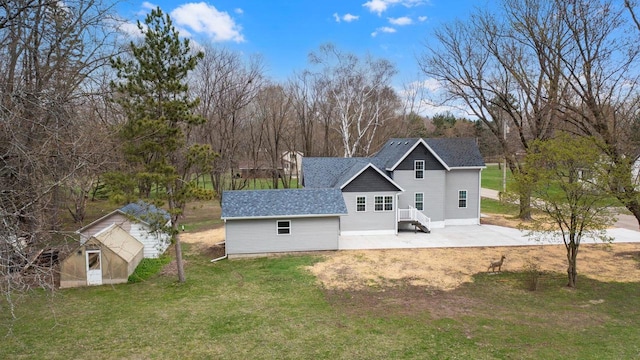 back of property with a lawn, an outbuilding, a shingled roof, and a storage shed