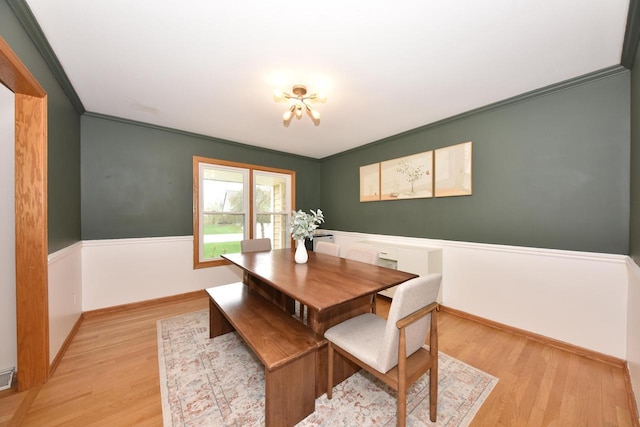 dining room with an inviting chandelier, light wood finished floors, crown molding, and baseboards