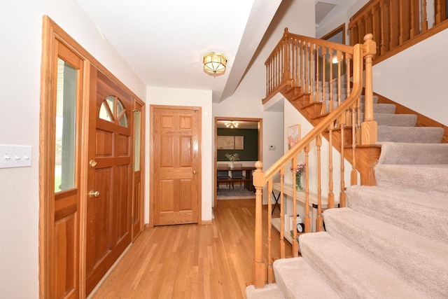 entryway featuring baseboards, light wood finished floors, and stairway