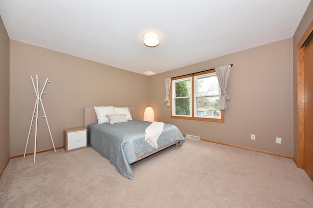 bedroom with baseboards, visible vents, and light carpet