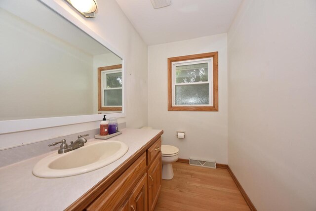 bathroom featuring visible vents, wood finished floors, toilet, and vanity