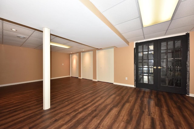 finished below grade area with baseboards, a paneled ceiling, wood finished floors, and french doors