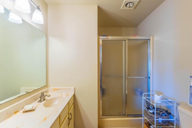 full bathroom with vanity, a shower stall, and toilet