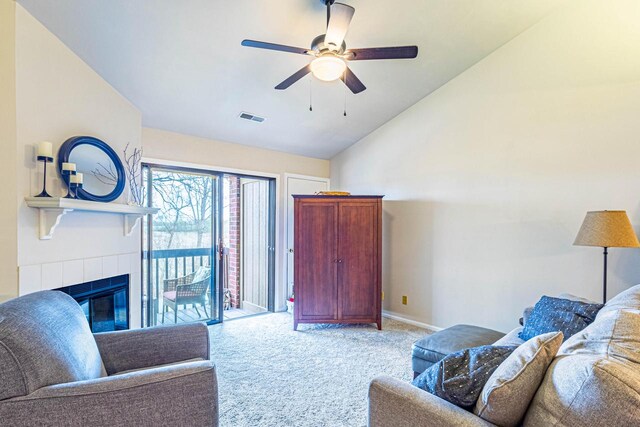 living room featuring light colored carpet, a tiled fireplace, a ceiling fan, lofted ceiling, and visible vents