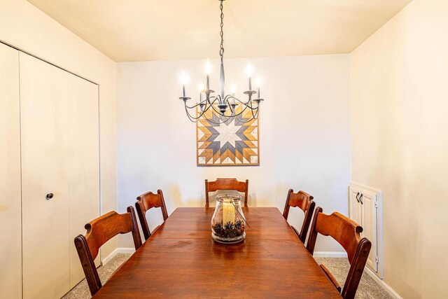 carpeted dining space with baseboards and a notable chandelier