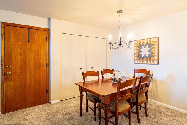 dining space featuring baseboards, light carpet, and a notable chandelier