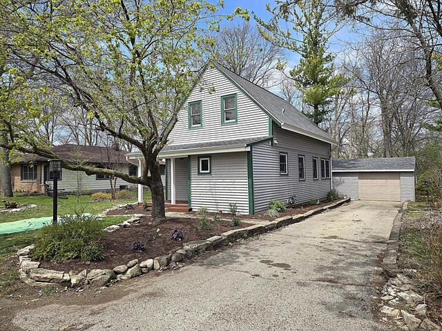 view of home's exterior featuring a detached garage, a shingled roof, and an outdoor structure