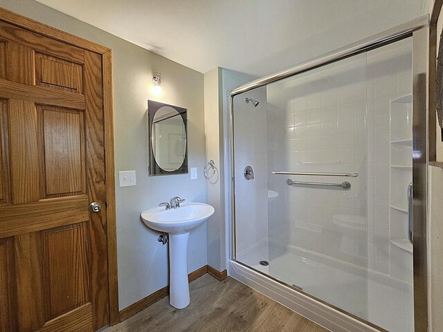 full bathroom featuring baseboards, a sink, wood finished floors, and a shower stall