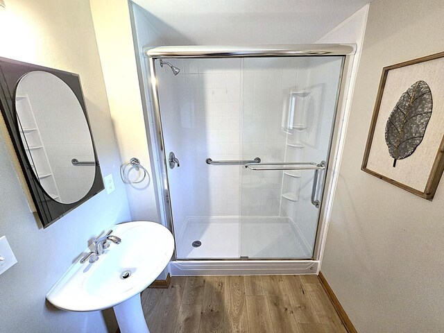 full bathroom featuring a sink, baseboards, a stall shower, and wood finished floors