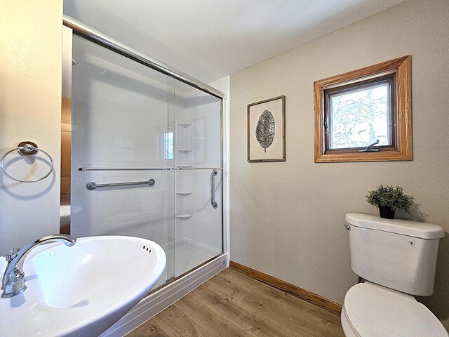 full bath featuring toilet, baseboards, a shower stall, and wood finished floors