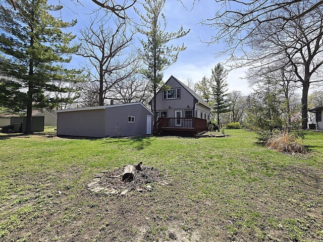 exterior space with an outdoor structure, a yard, an outdoor fire pit, and a deck
