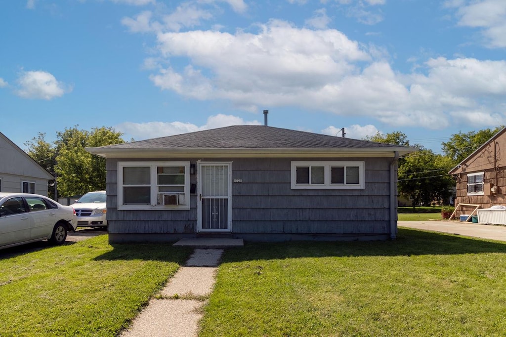 bungalow-style house featuring a shingled roof and a front yard
